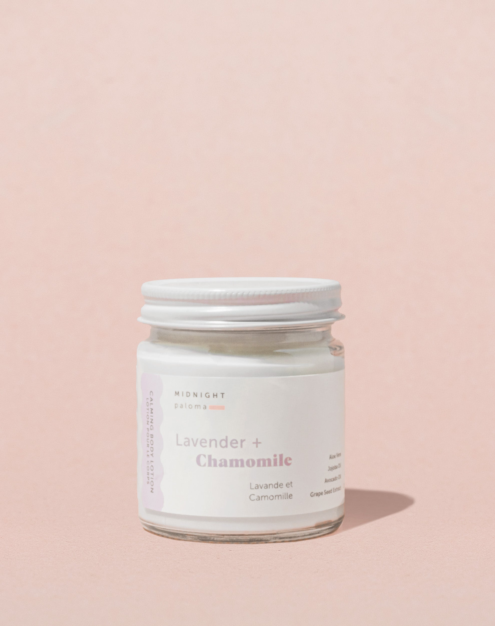 A glass jar with a white label containing the product Lavender + Chamomile Body Lotion.
