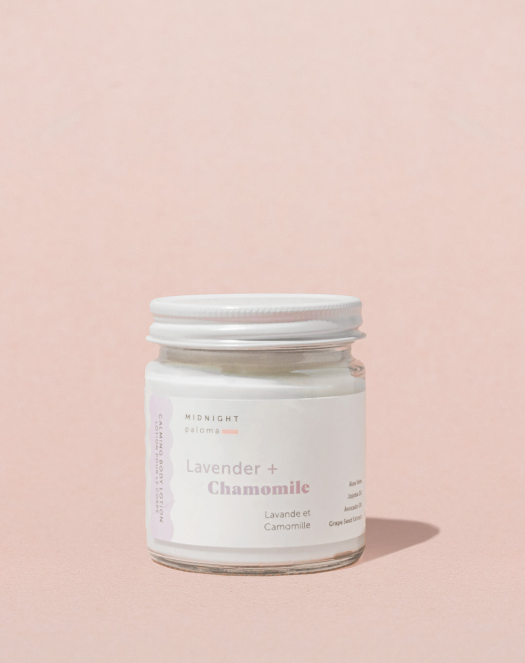 A glass jar with a white label containing the product Lavender + Chamomile Body Lotion.