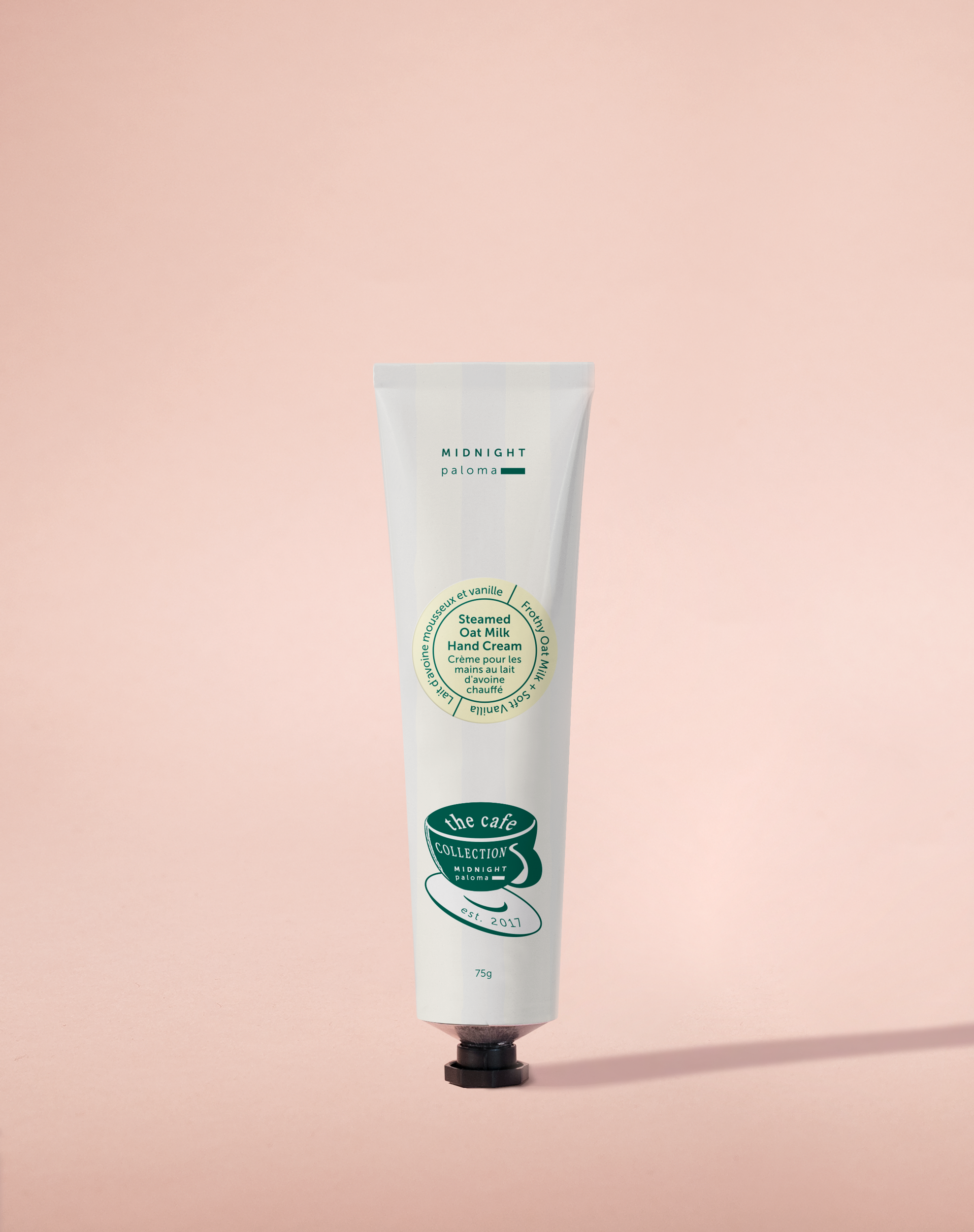 A tube of hand cream with a label that includes a green leafy design and text, placed against a pink background.