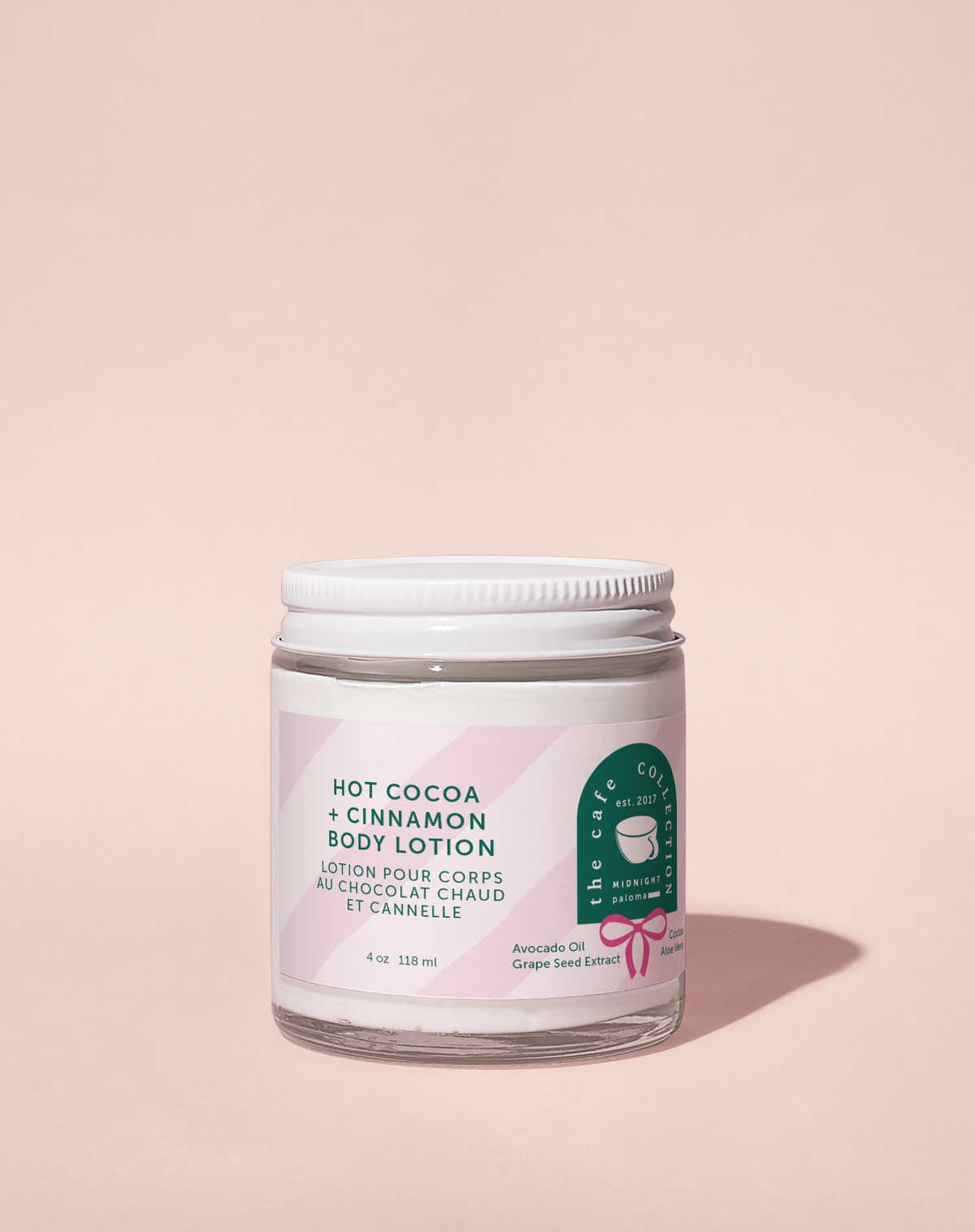 Body lotion jar labeled 'Hot Cocoa + Cinnamon' on a beige background