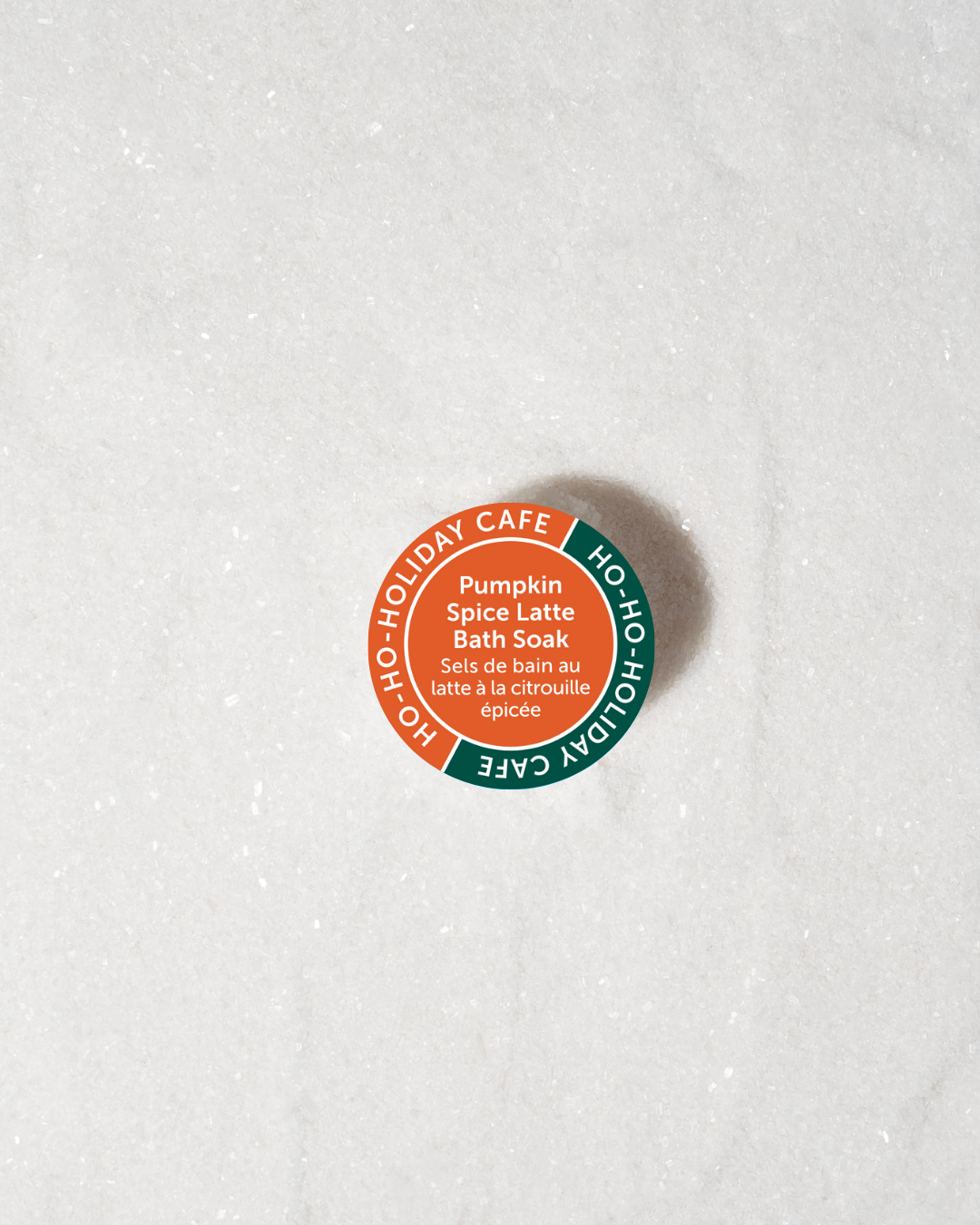 Round container labeled 'Pumpkin Spice Latte Bath Soak' from 'Ho Ho Holiday Cafe' on a white background