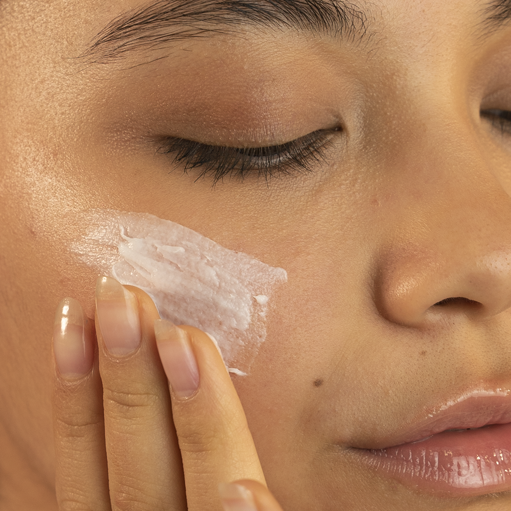 A jar of cleansing balm with a label that reads 'Cleansing Balm' and lists burdock root, cucumber, and chamomile as ingredients. 